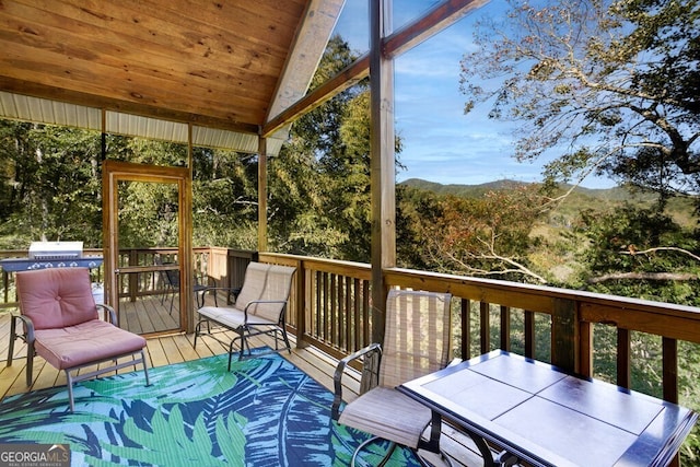 sunroom / solarium with vaulted ceiling, a mountain view, and plenty of natural light