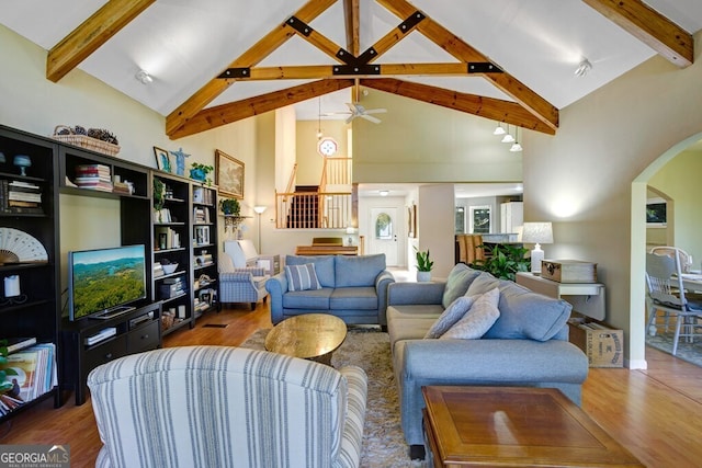 living room featuring hardwood / wood-style flooring, ceiling fan, beam ceiling, and high vaulted ceiling