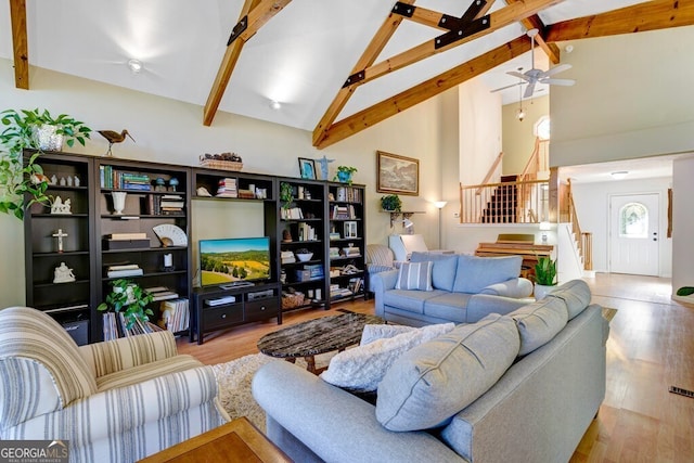 living room with high vaulted ceiling, beam ceiling, ceiling fan, and light hardwood / wood-style flooring