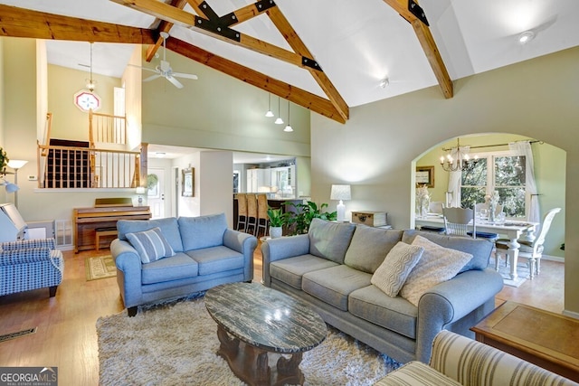 living room with high vaulted ceiling, beamed ceiling, ceiling fan with notable chandelier, and light hardwood / wood-style flooring