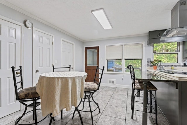 dining room featuring crown molding, light tile patterned flooring, and a textured ceiling