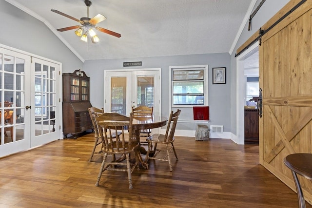 dining room featuring french doors, a textured ceiling, wood-type flooring, a barn door, and lofted ceiling