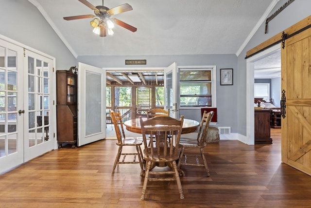 dining space with hardwood / wood-style floors, lofted ceiling, french doors, a barn door, and a textured ceiling