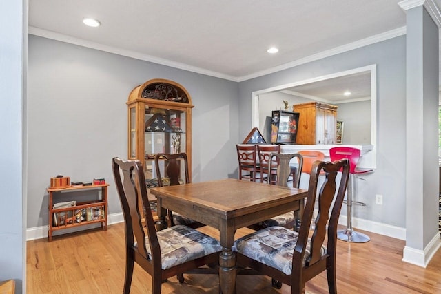 dining space with crown molding and light hardwood / wood-style floors