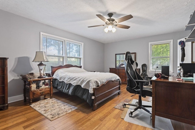 bedroom featuring multiple windows, ceiling fan, light hardwood / wood-style flooring, and a textured ceiling