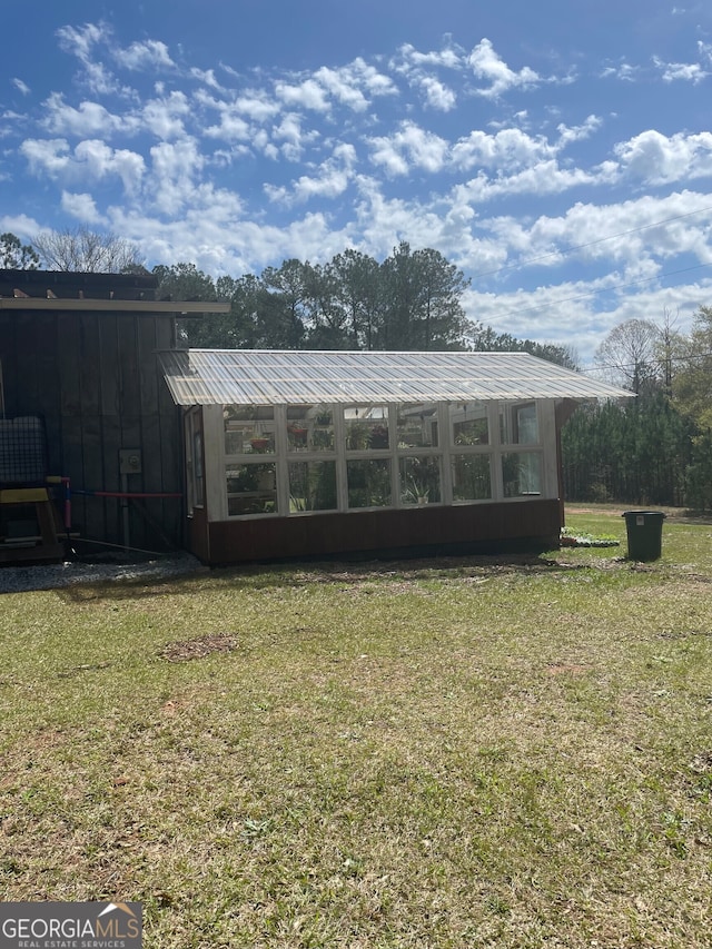 view of outbuilding with a lawn and a sunroom