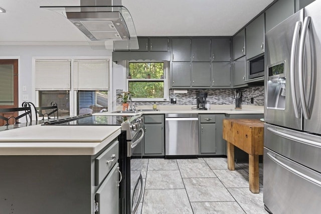 kitchen featuring gray cabinetry, stainless steel appliances, tasteful backsplash, light tile patterned flooring, and ornamental molding