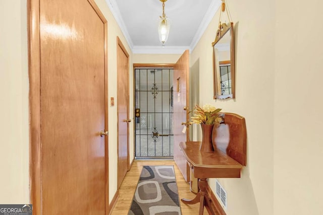 doorway to outside featuring light hardwood / wood-style floors and crown molding