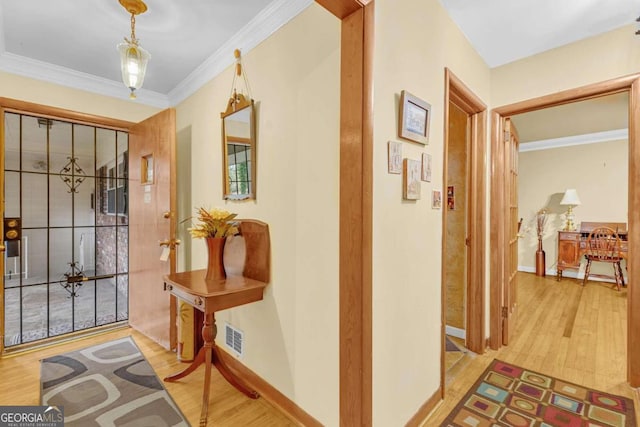 foyer with ornamental molding and light hardwood / wood-style floors