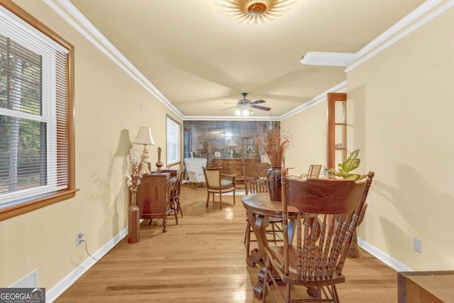 dining area with light wood-type flooring, a healthy amount of sunlight, and crown molding