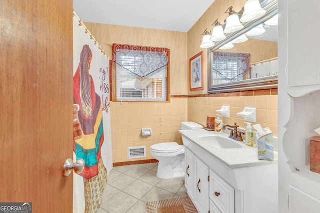 bathroom with toilet, vanity, tile walls, and tile patterned floors