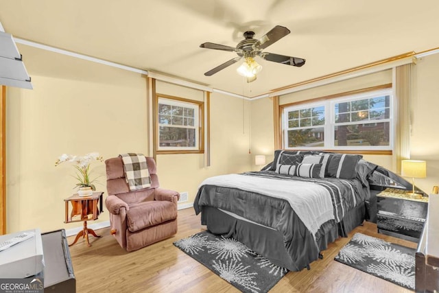 bedroom with ceiling fan, multiple windows, and light hardwood / wood-style flooring