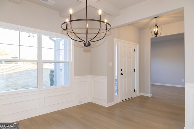 entrance foyer with hardwood / wood-style flooring, beamed ceiling, and an inviting chandelier