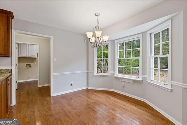 unfurnished dining area with wood-type flooring and a chandelier