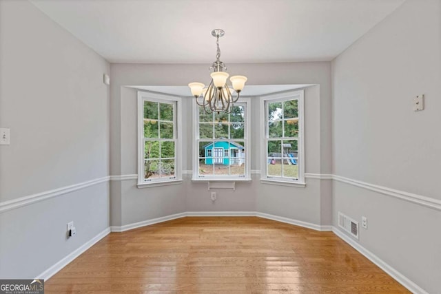 unfurnished dining area with light hardwood / wood-style flooring and a notable chandelier