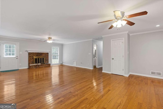 unfurnished living room featuring ceiling fan, wood-type flooring, crown molding, and a brick fireplace