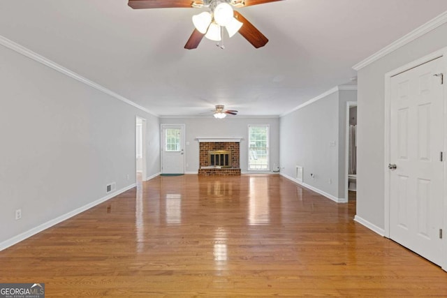 unfurnished living room with a brick fireplace, ceiling fan, light wood-type flooring, and crown molding