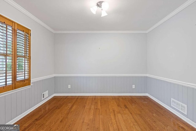 empty room with hardwood / wood-style flooring, wooden walls, and crown molding