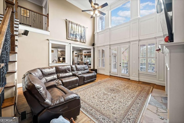 living room featuring ornamental molding, a fireplace, a towering ceiling, and hardwood / wood-style flooring