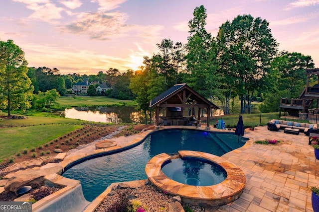 pool at dusk with a patio, a water view, a gazebo, and an in ground hot tub