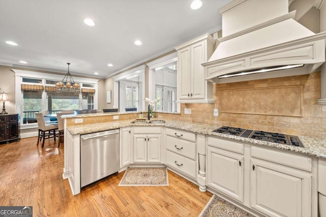 kitchen with light hardwood / wood-style floors, light stone counters, appliances with stainless steel finishes, a kitchen breakfast bar, and backsplash