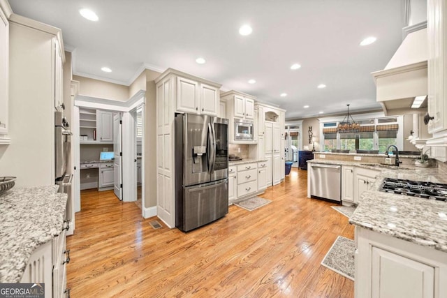 kitchen featuring light hardwood / wood-style floors, ornamental molding, backsplash, light stone countertops, and appliances with stainless steel finishes