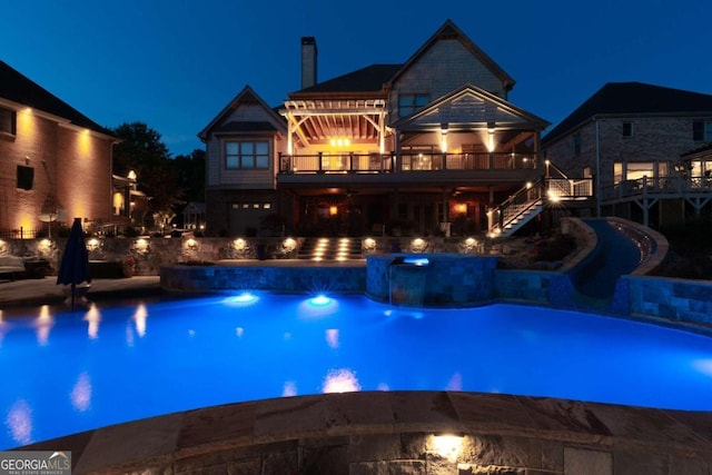 pool at night featuring an in ground hot tub