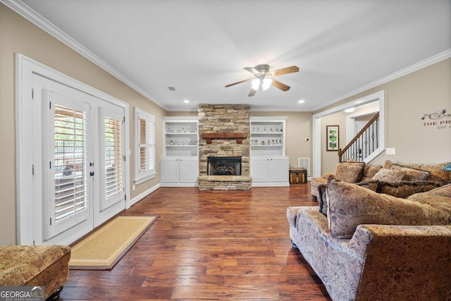 living room with a fireplace, dark hardwood / wood-style floors, crown molding, and built in shelves