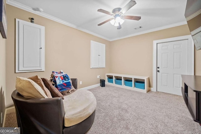 sitting room with ceiling fan, crown molding, and carpet floors