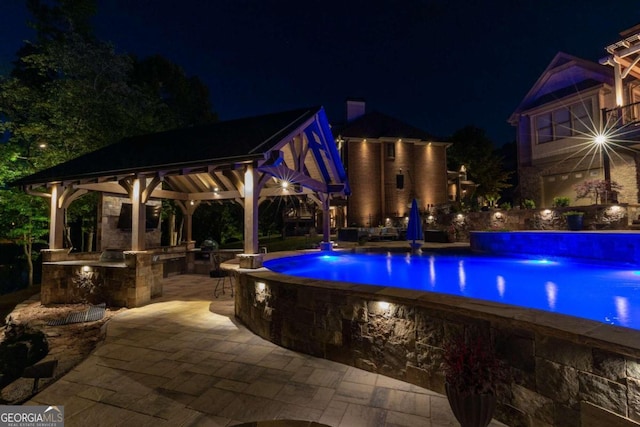 pool at dusk with a patio and a gazebo