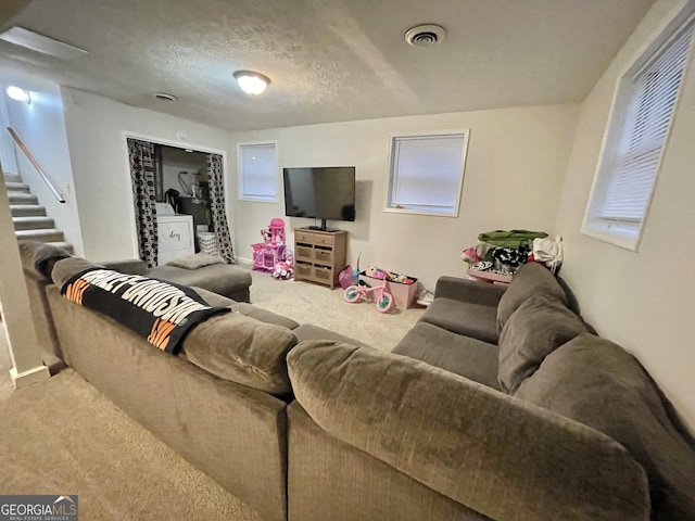 living room featuring carpet flooring, a textured ceiling, and washer / dryer