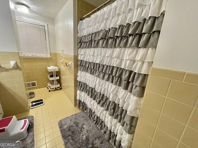 bathroom featuring a textured ceiling, tile patterned flooring, tile walls, and a shower with shower curtain