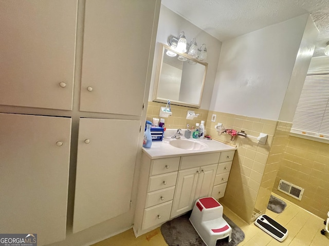 bathroom featuring a textured ceiling, vanity, tile walls, and tile patterned flooring