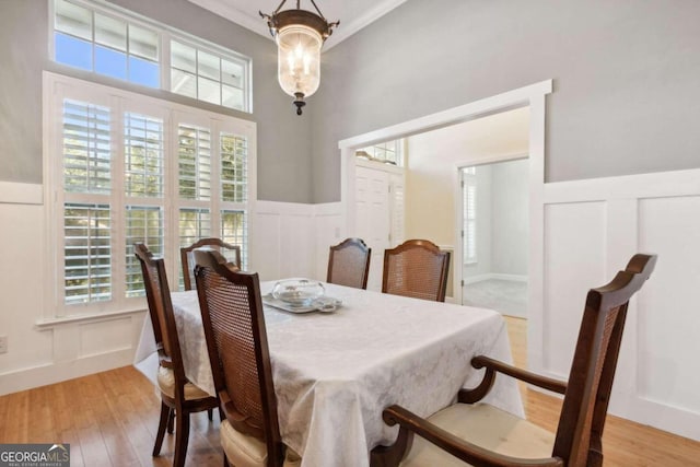 dining space with crown molding, a wealth of natural light, light hardwood / wood-style floors, and a chandelier