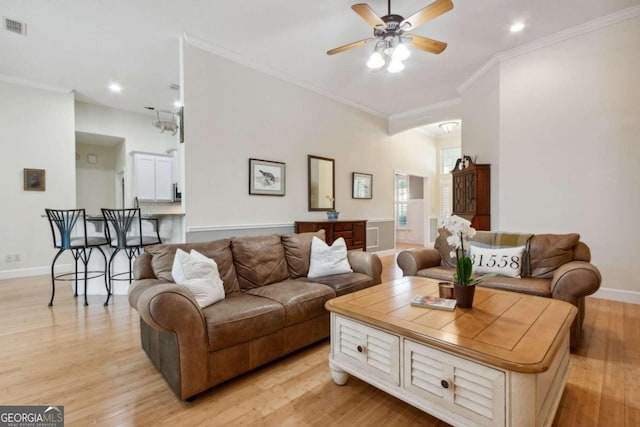 living room with light wood-type flooring, ceiling fan, and crown molding