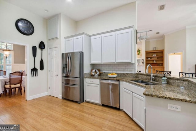 kitchen with white cabinetry, appliances with stainless steel finishes, dark stone countertops, and light hardwood / wood-style flooring