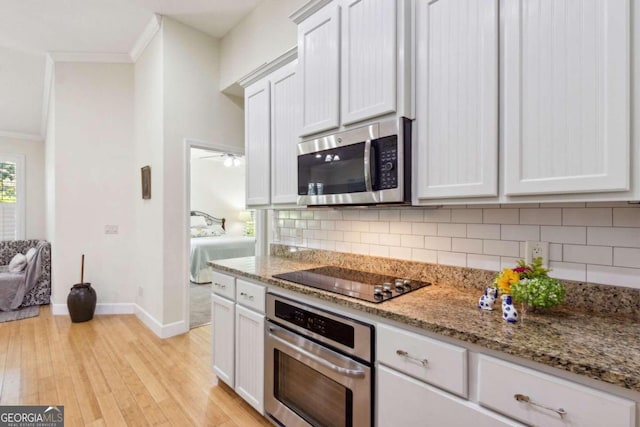 kitchen featuring stone countertops, appliances with stainless steel finishes, light hardwood / wood-style flooring, crown molding, and white cabinets