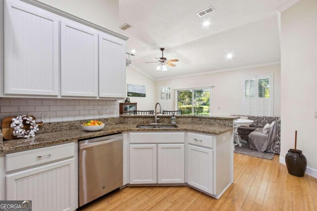 kitchen featuring stainless steel dishwasher, white cabinetry, sink, and lofted ceiling