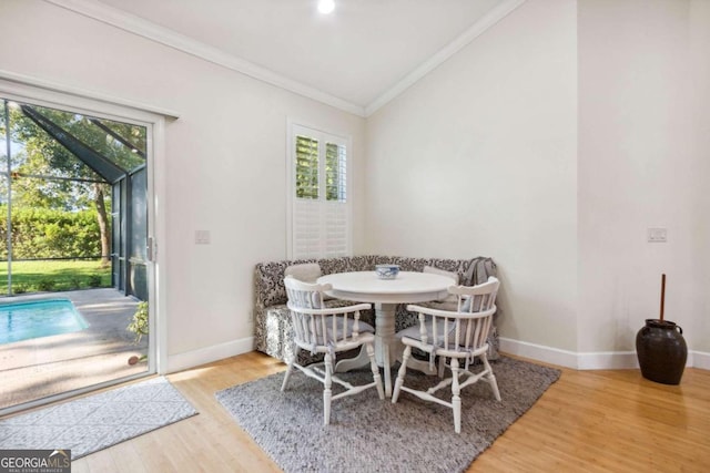 dining area featuring ornamental molding, hardwood / wood-style floors, vaulted ceiling, and a healthy amount of sunlight