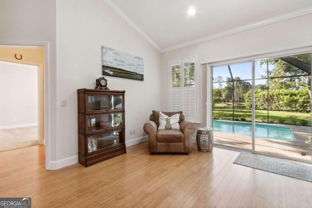 living area featuring light hardwood / wood-style floors, lofted ceiling, and ornamental molding