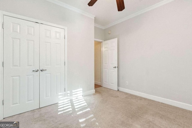 unfurnished bedroom with ornamental molding, light carpet, ceiling fan, and a closet