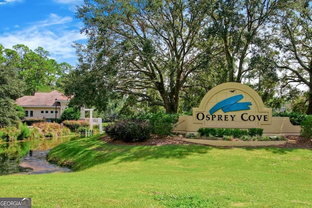 community sign featuring a yard and a water view