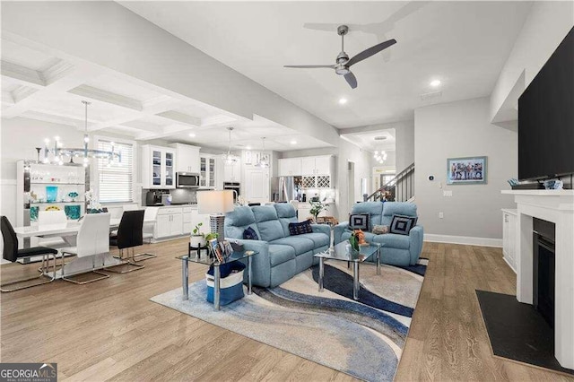 living room featuring ceiling fan, beam ceiling, light wood-type flooring, and coffered ceiling