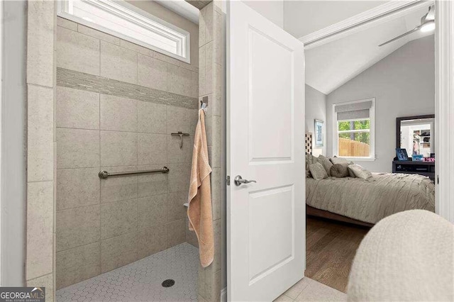 bathroom featuring ceiling fan, hardwood / wood-style floors, vaulted ceiling, and tiled shower