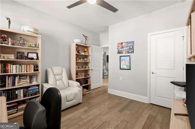 living area featuring hardwood / wood-style floors and ceiling fan