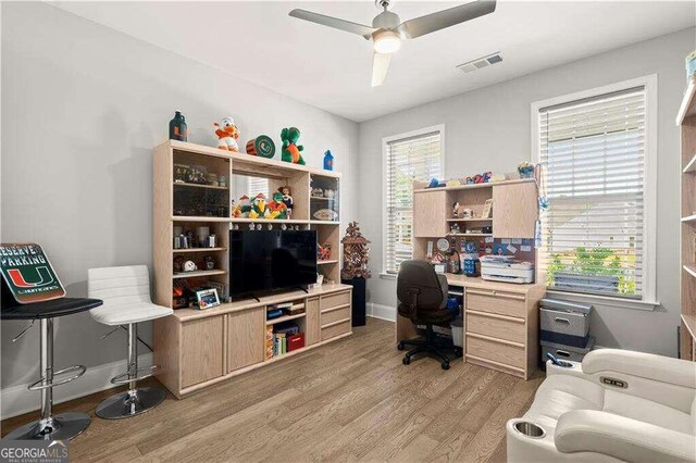 home office with light hardwood / wood-style floors and ceiling fan