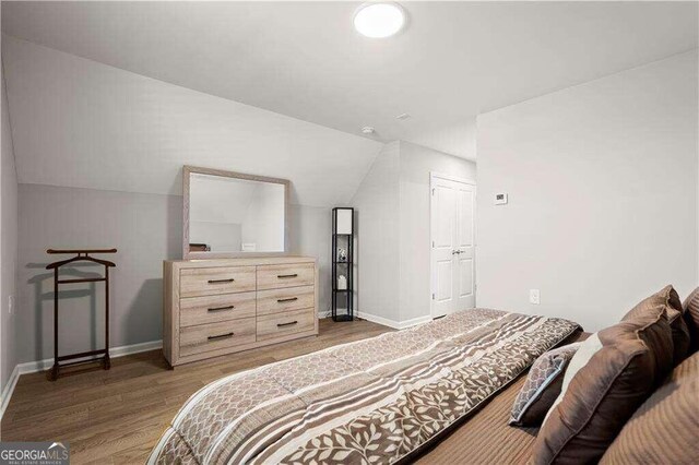 bedroom with wood-type flooring and lofted ceiling