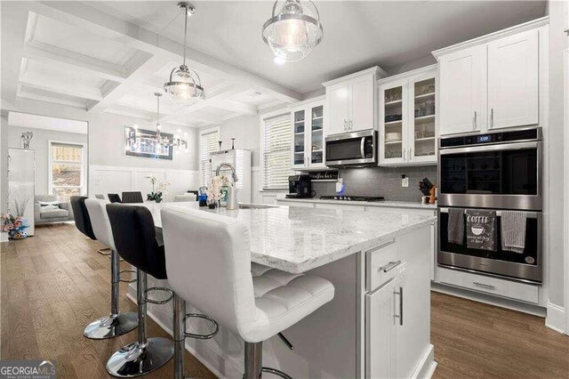 kitchen featuring dark wood-type flooring, white cabinets, a kitchen island with sink, and stainless steel appliances