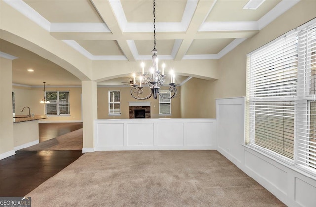 unfurnished dining area with hardwood / wood-style floors, sink, coffered ceiling, ornamental molding, and beam ceiling