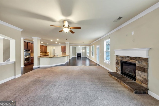 unfurnished living room with a fireplace, ceiling fan, sink, and ornamental molding